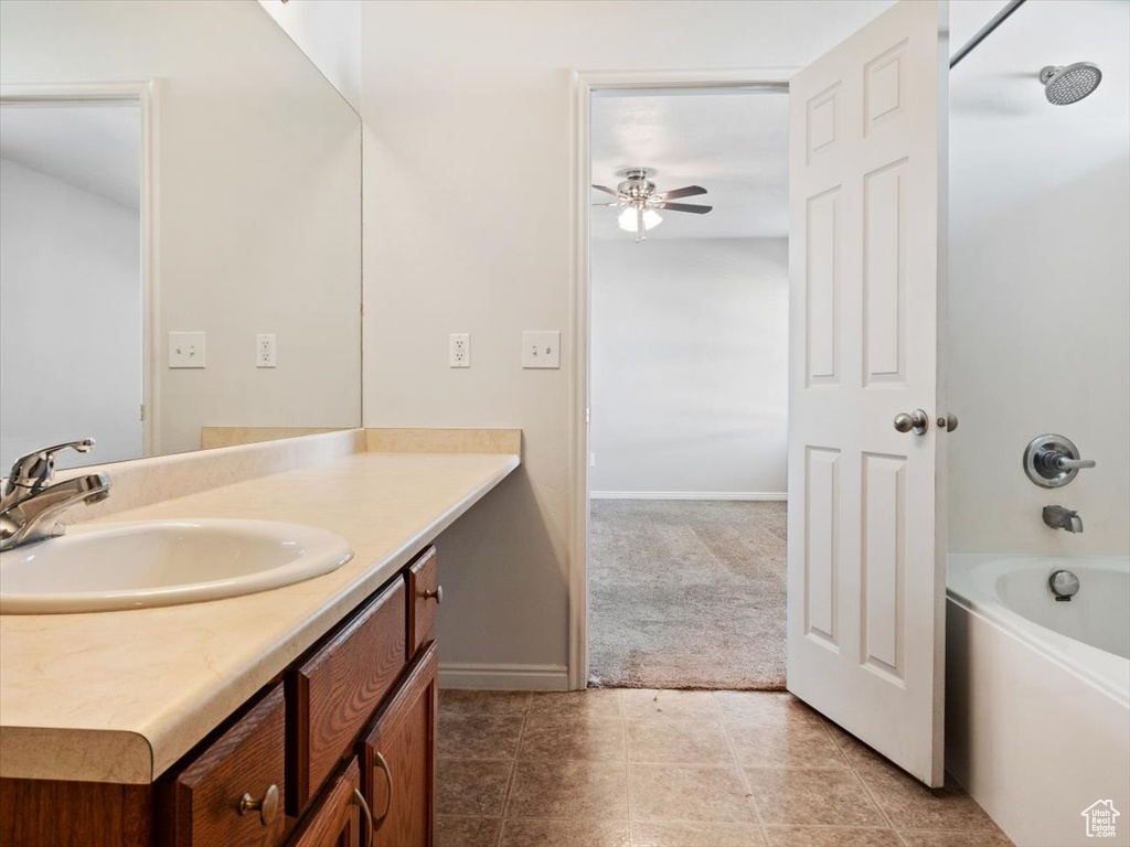 Bathroom featuring bathtub / shower combination, vanity with extensive cabinet space, tile flooring, and ceiling fan