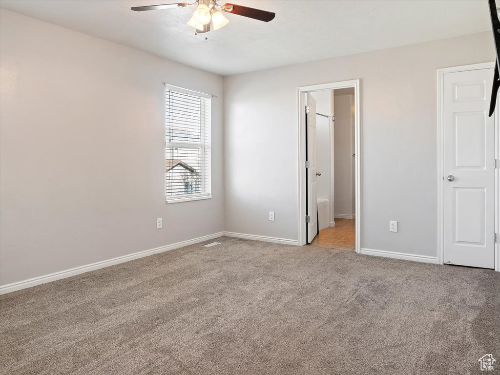Unfurnished bedroom featuring ensuite bathroom, light colored carpet, and ceiling fan
