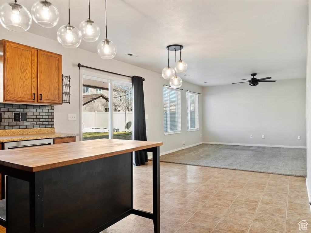 Kitchen with tasteful backsplash, hanging light fixtures, light tile floors, butcher block countertops, and ceiling fan