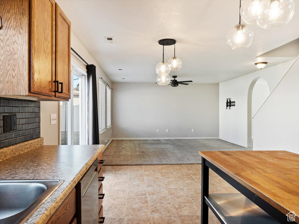 Kitchen with light tile floors, ceiling fan with notable chandelier, tasteful backsplash, and hanging light fixtures