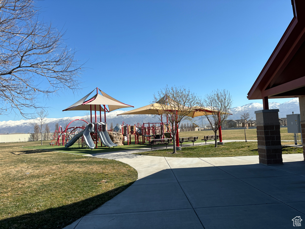 Exterior space with a mountain view, a playground, and a lawn