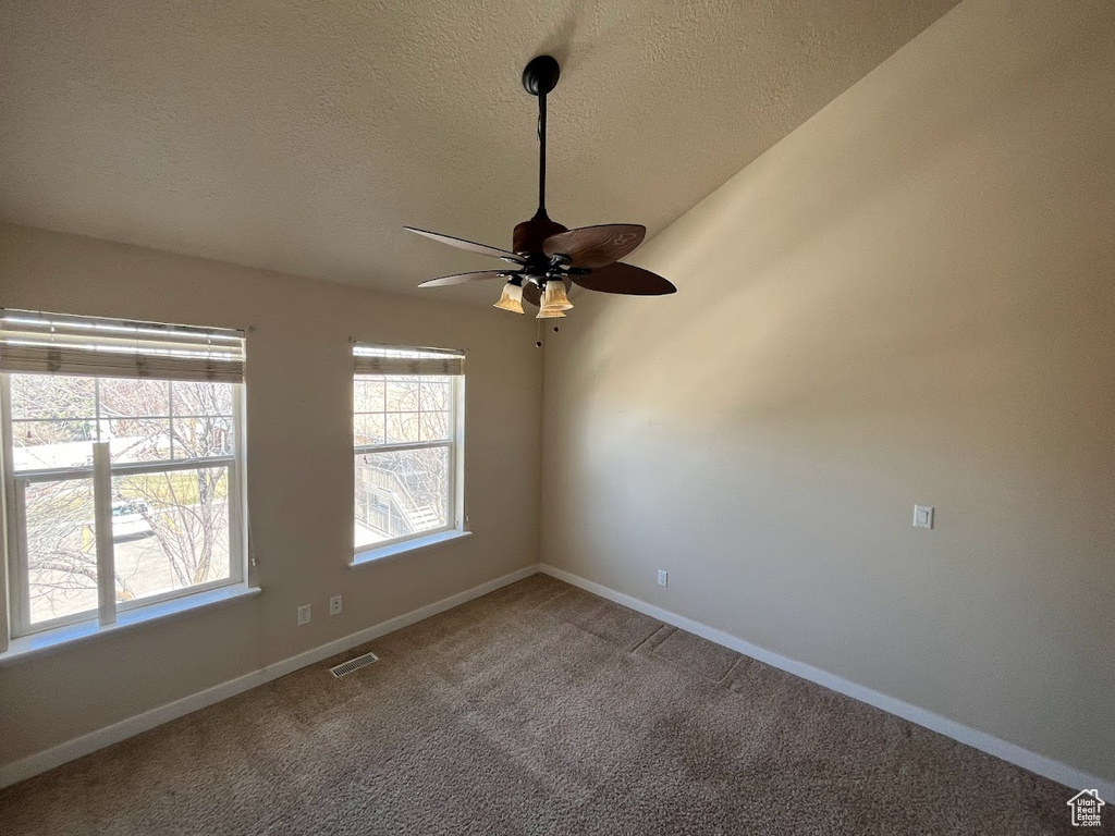 Spare room featuring carpet floors, a textured ceiling, and ceiling fan