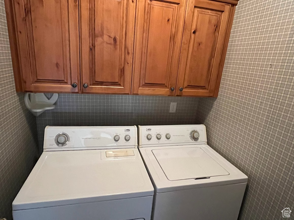 Washroom with separate washer and dryer, cabinets, and tile walls