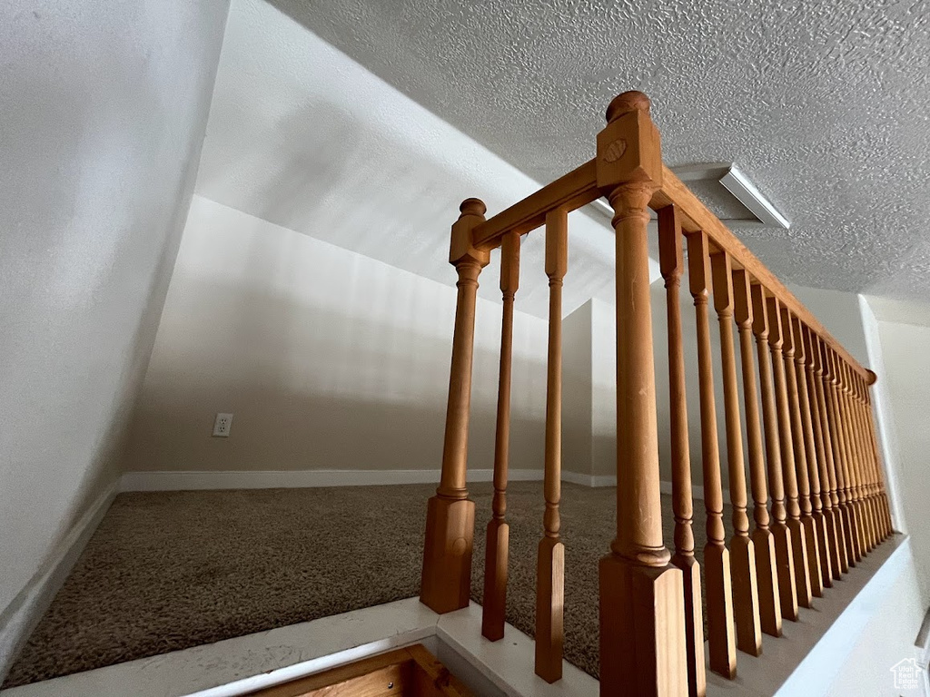 Stairway featuring a textured ceiling and carpet