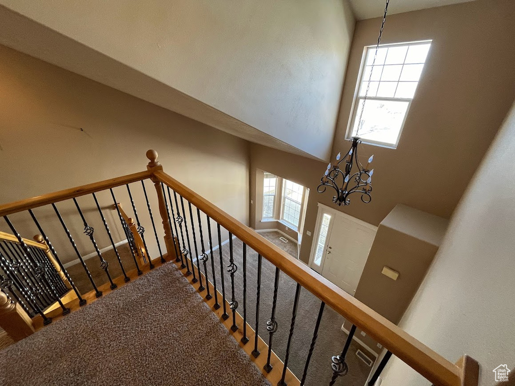 Stairs featuring a wealth of natural light, a chandelier, and a high ceiling