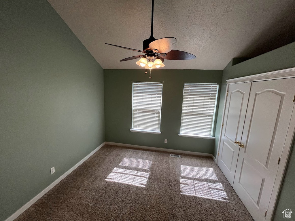 Unfurnished bedroom with light colored carpet, vaulted ceiling, ceiling fan, and a closet