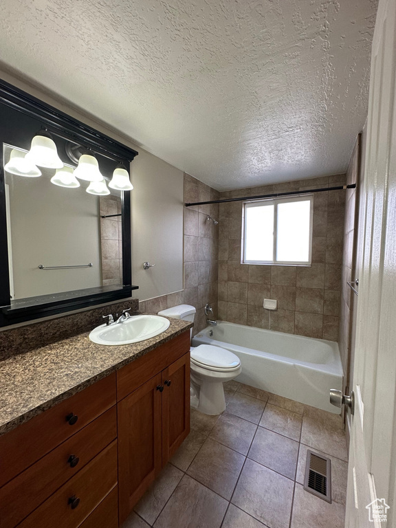 Full bathroom with tile flooring, tiled shower / bath, large vanity, and toilet