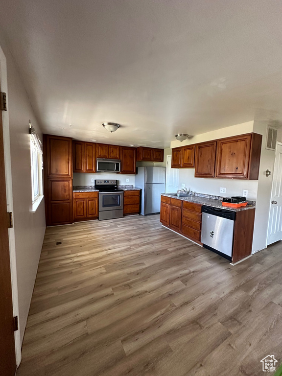 Kitchen with stainless steel appliances, sink, and light hardwood / wood-style flooring