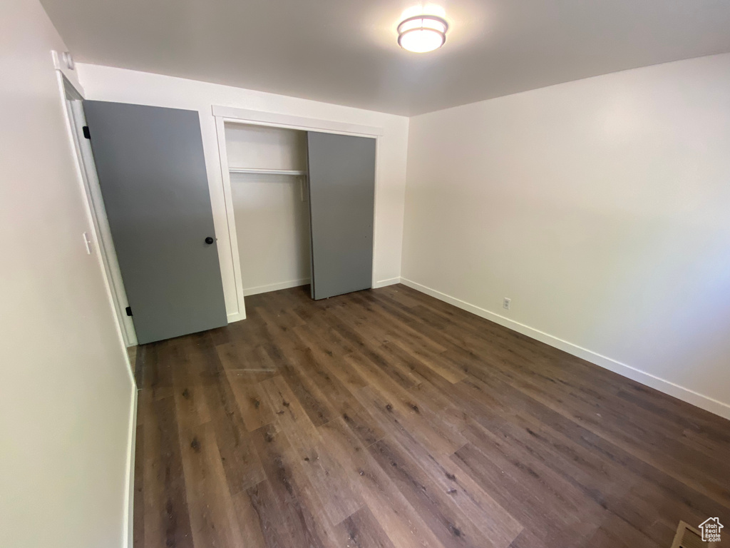 Unfurnished bedroom with dark hardwood / wood-style floors and a closet