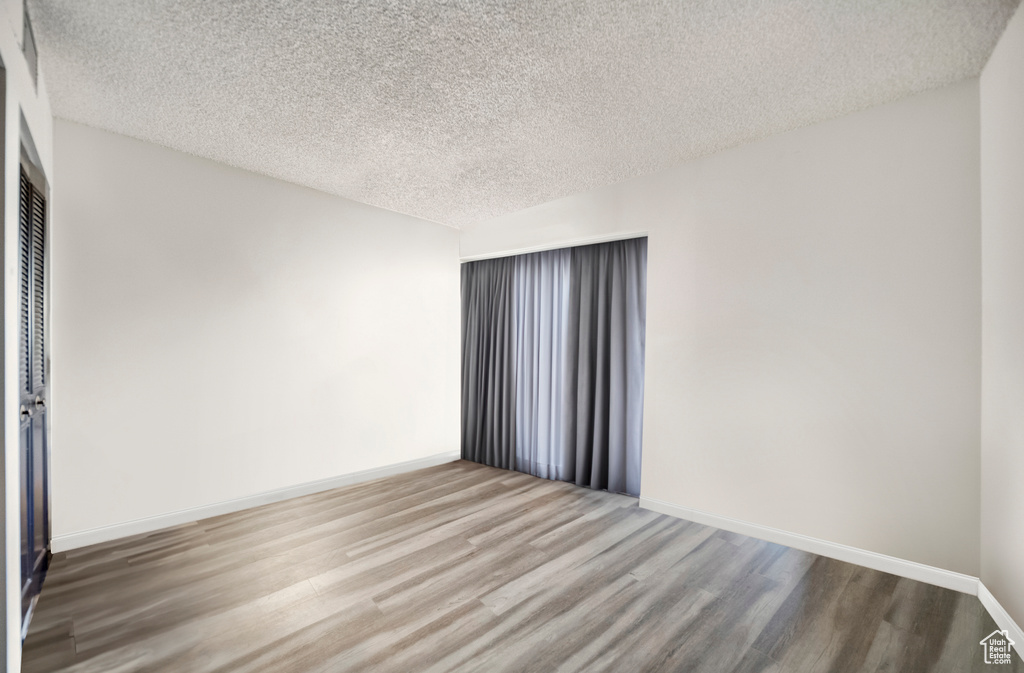 Empty room featuring a textured ceiling and hardwood / wood-style floors