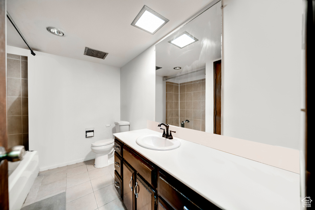 Full bathroom featuring tile flooring, tiled shower / bath, large vanity, and toilet