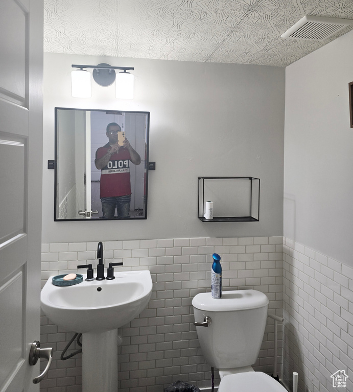 Bathroom with tile walls, sink, backsplash, and toilet