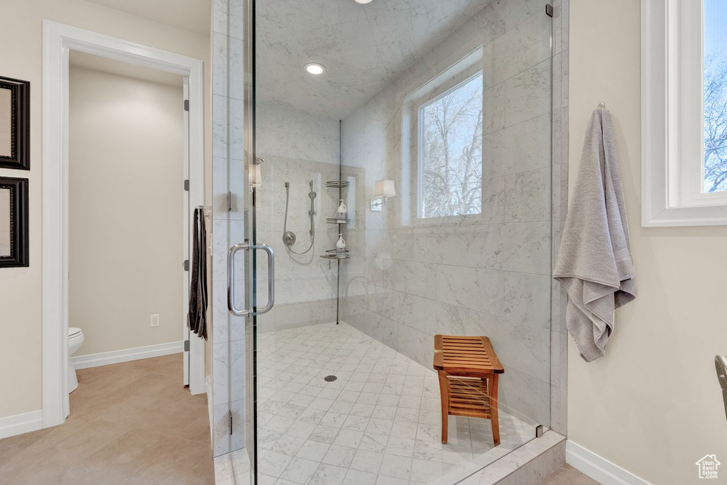 Bathroom featuring plenty of natural light, toilet, tile floors, and an enclosed shower