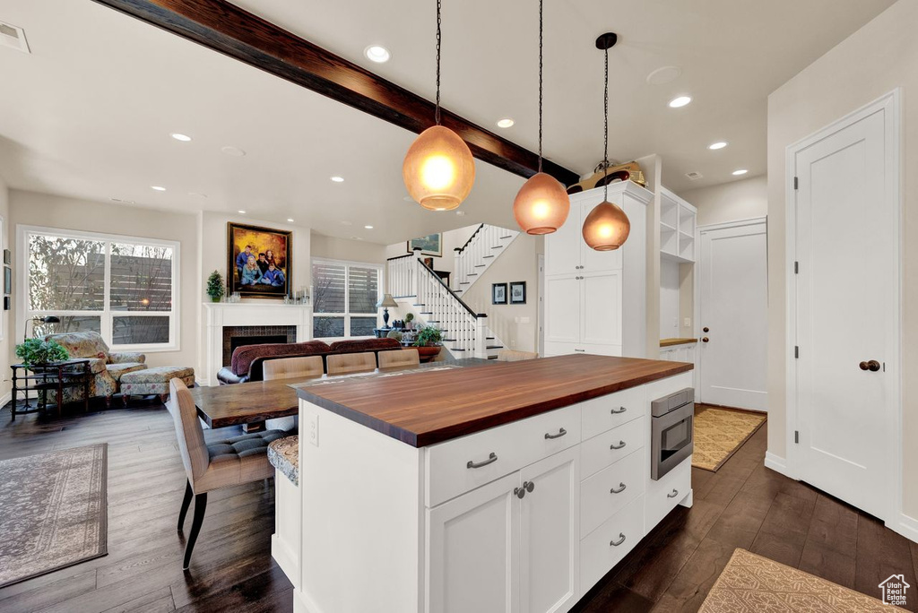 Kitchen with hanging light fixtures, dark hardwood / wood-style flooring, beam ceiling, and white cabinets