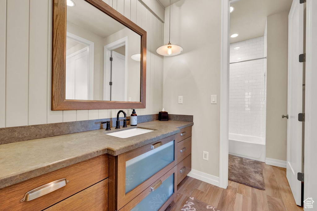 Bathroom with tiled shower / bath, vanity, and wood-type flooring