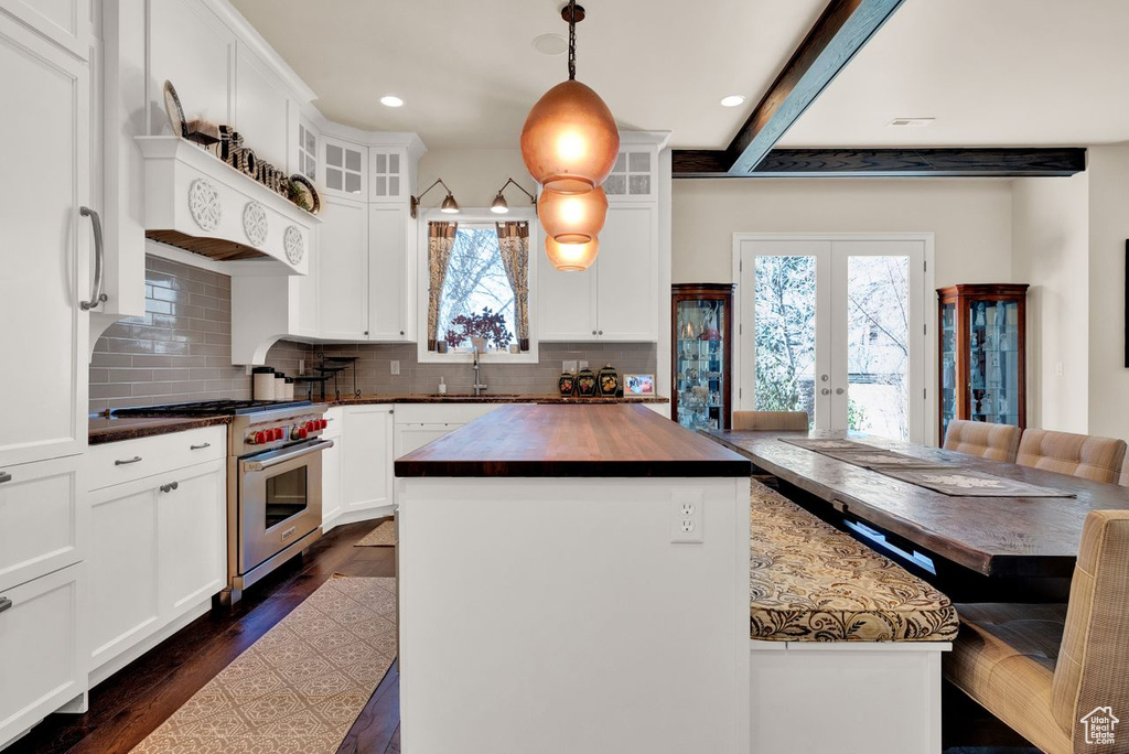 Kitchen featuring pendant lighting, white cabinetry, designer range, tasteful backsplash, and a kitchen island