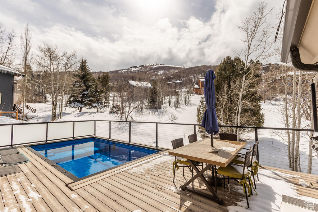 Snow covered pool with a deck with mountain view