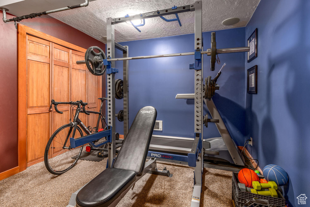 Workout area featuring carpet floors and a textured ceiling