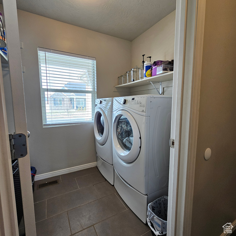 Laundry area featuring dark tile floors and independent washer and dryer