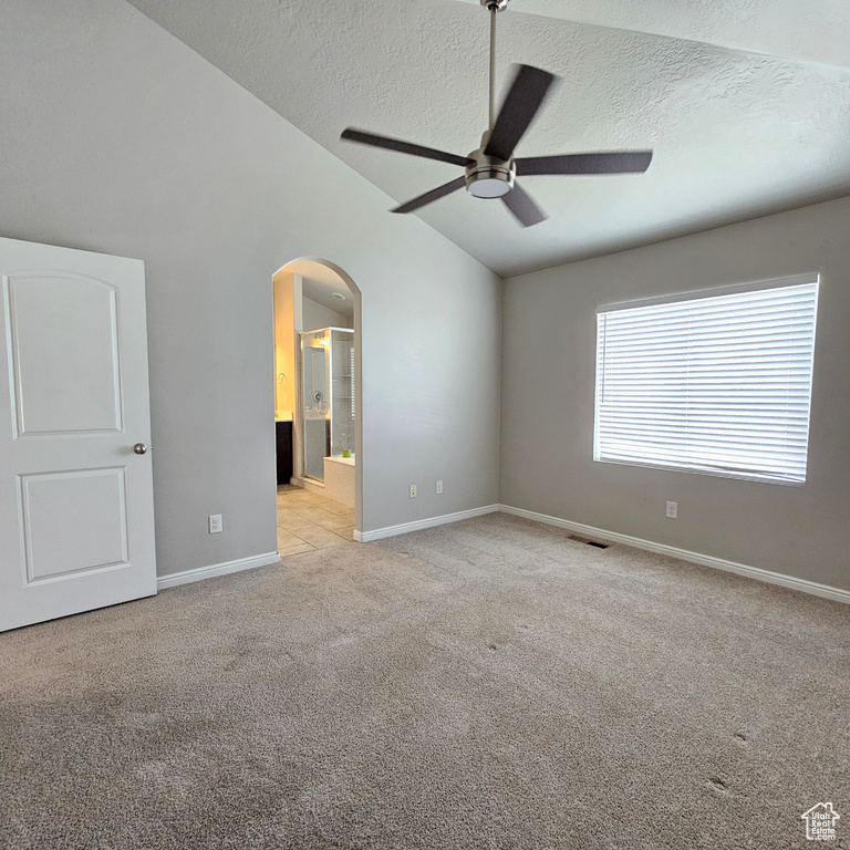 Carpeted spare room featuring a textured ceiling, ceiling fan, and high vaulted ceiling