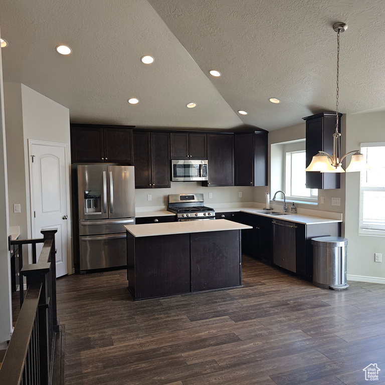 Kitchen featuring stainless steel appliances, a kitchen island, decorative light fixtures, and dark hardwood / wood-style floors