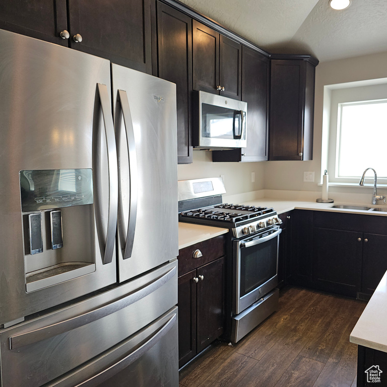 Kitchen with sink, dark hardwood / wood-style flooring, stainless steel appliances, and dark brown cabinetry