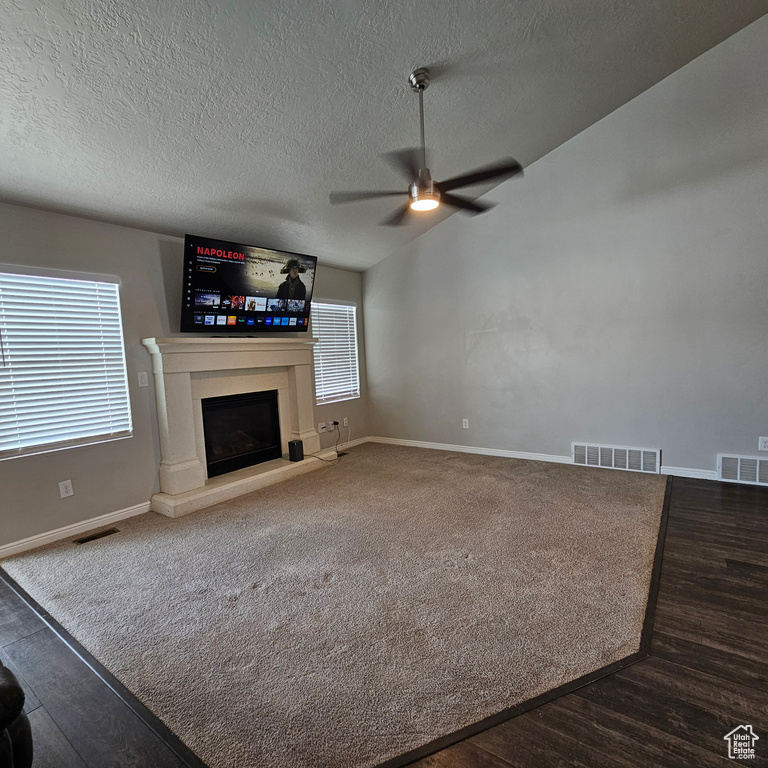 Unfurnished living room with ceiling fan, a textured ceiling, and dark colored carpet