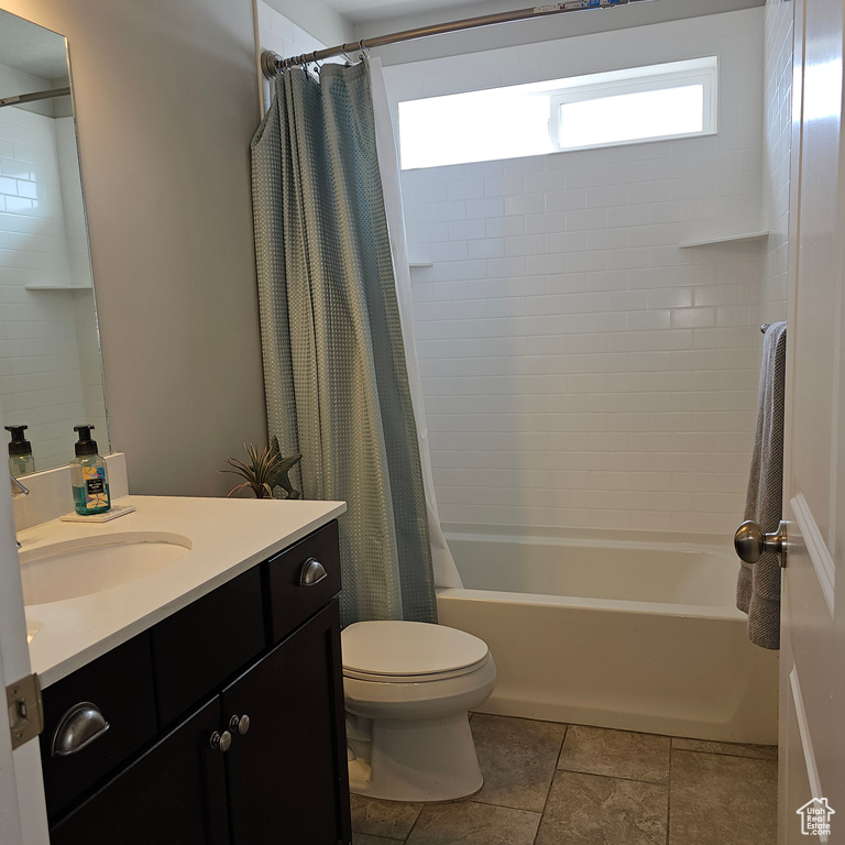 Full bathroom featuring toilet, shower / bathtub combination with curtain, tile floors, and vanity