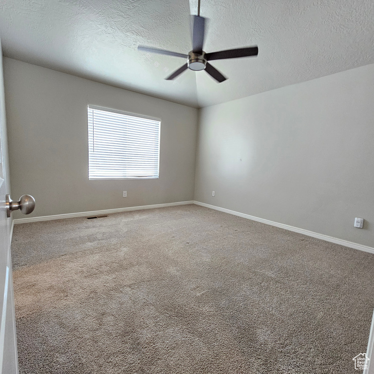 Spare room with ceiling fan, a textured ceiling, and carpet