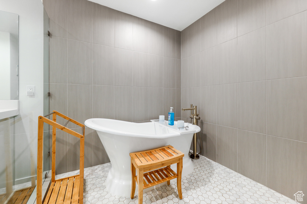 Bathroom featuring tile walls, tile floors, and a bath