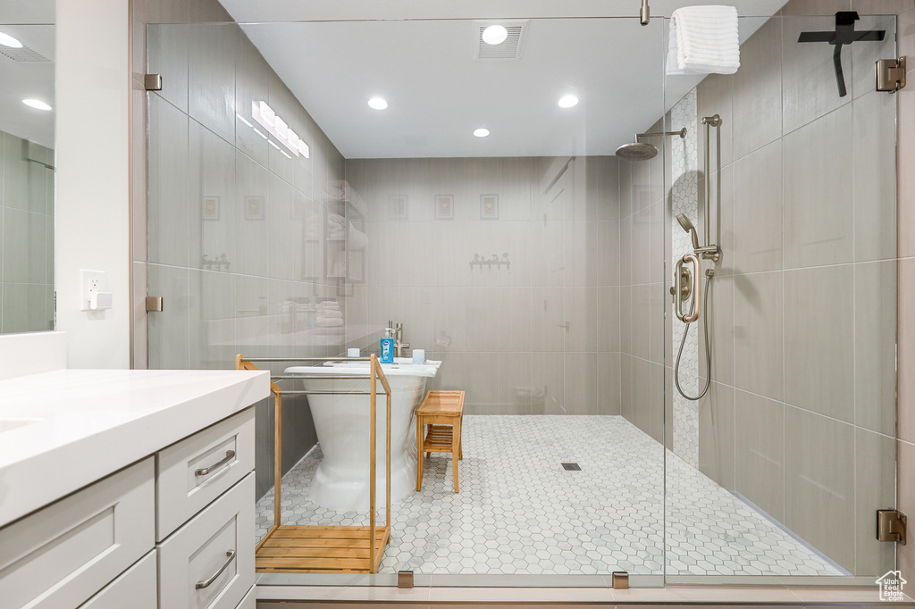 Bathroom featuring tile flooring, tile walls, an enclosed shower, and vanity