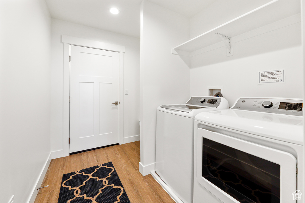 Laundry area with light hardwood / wood-style floors, hookup for a washing machine, and separate washer and dryer