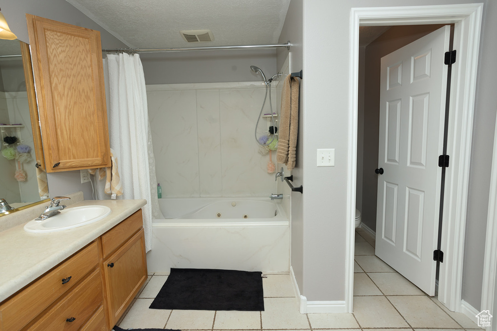 Bathroom featuring tile flooring, vanity with extensive cabinet space, shower / tub combo, and a textured ceiling