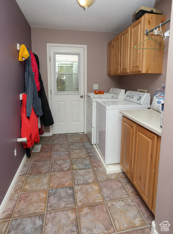 Washroom with a textured ceiling, cabinets, light tile floors, and independent washer and dryer