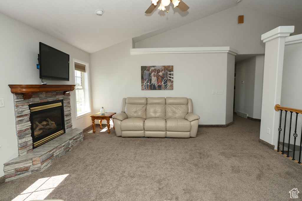 Carpeted living room with lofted ceiling, a fireplace, and ceiling fan