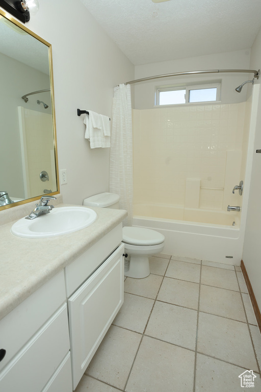 Full bathroom with tile floors, shower / tub combo with curtain, toilet, and oversized vanity