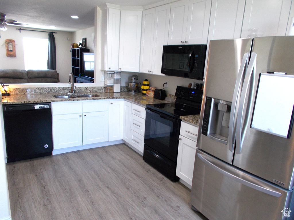 Kitchen featuring white cabinetry, black appliances, ceiling fan, and light hardwood / wood-style flooring