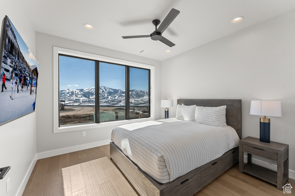 Bedroom with a mountain view, light hardwood / wood-style floors, and ceiling fan