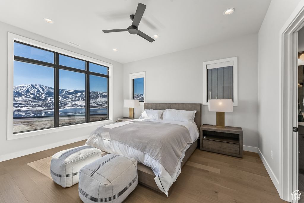 Bedroom featuring a mountain view, multiple windows, dark wood-type flooring, and ceiling fan