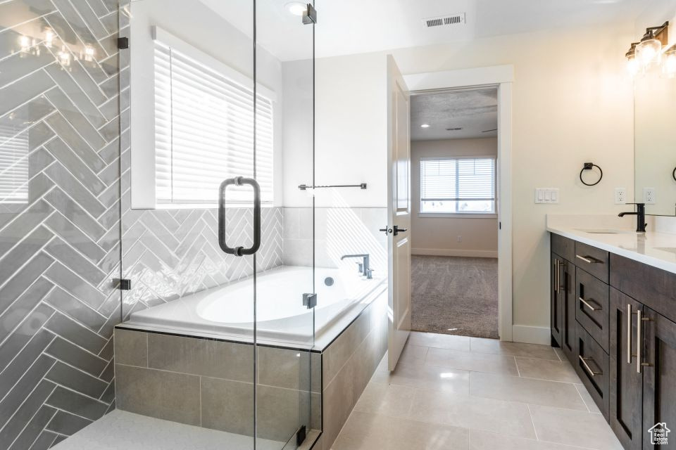 Bathroom with tile floors, large vanity, and tiled bath