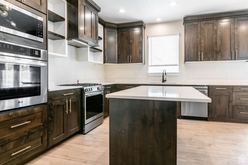 Kitchen featuring stainless steel appliances, light hardwood / wood-style flooring, sink, dark brown cabinetry, and a kitchen island