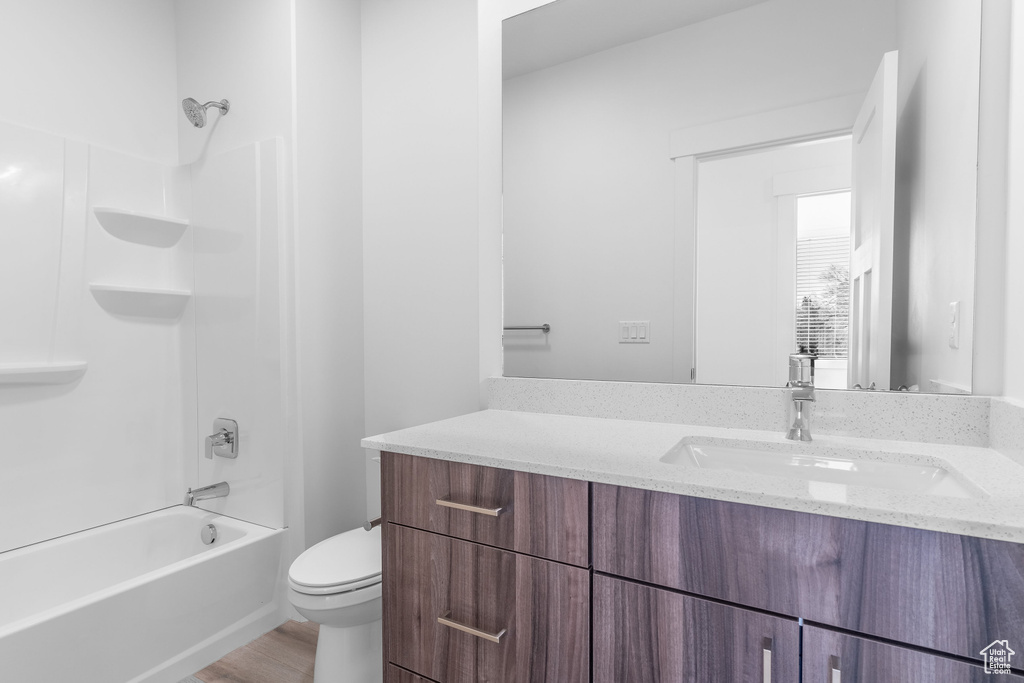 Full bathroom featuring hardwood / wood-style flooring,  shower combination, vanity, and toilet