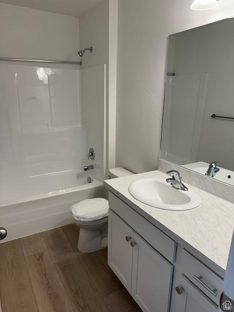 Full bathroom featuring shower / washtub combination, toilet, vanity, and hardwood / wood-style flooring