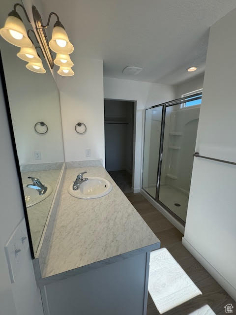 Bathroom featuring vanity, walk in shower, and a notable chandelier