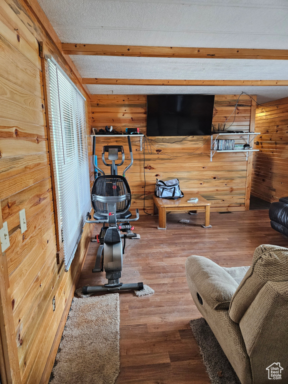 Workout room featuring wood walls, dark hardwood / wood-style flooring, and a textured ceiling