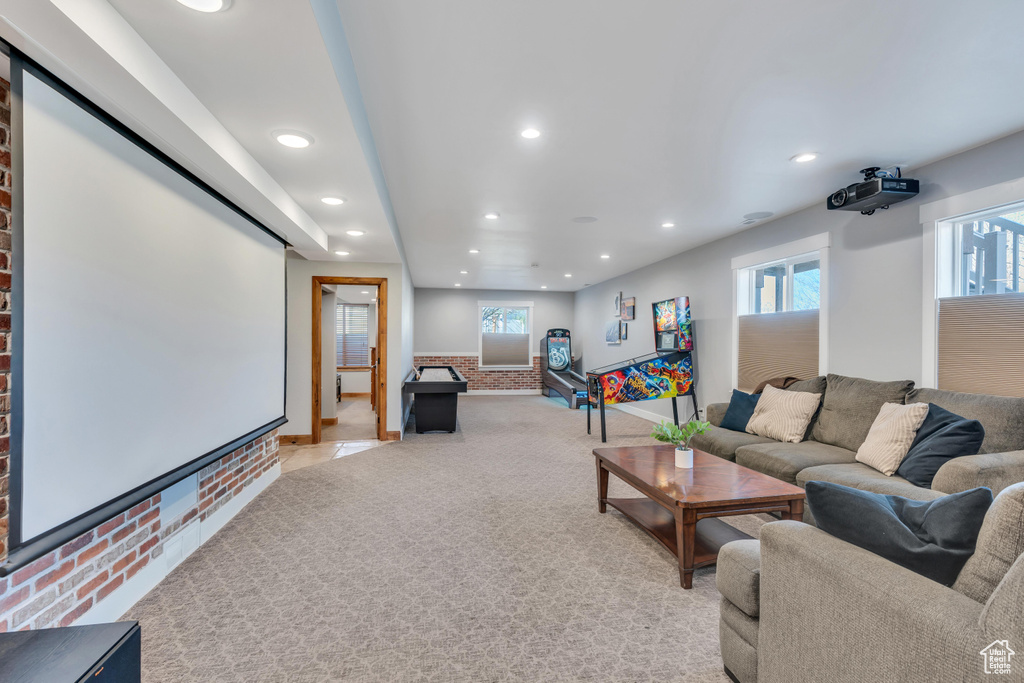 Carpeted home theater room featuring brick wall
