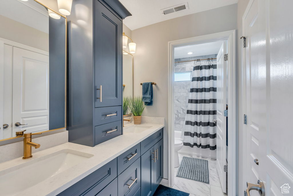 Full bathroom featuring dual vanity, shower / bath combo, toilet, and tile floors