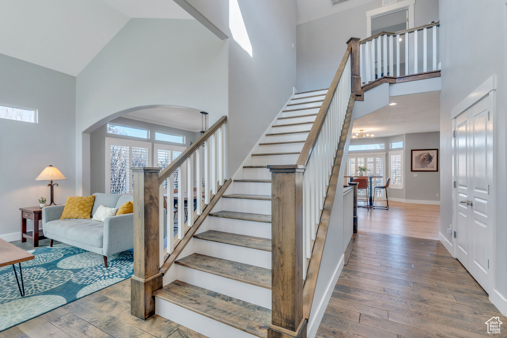 Staircase with high vaulted ceiling, light wood-type flooring, and a wealth of natural light