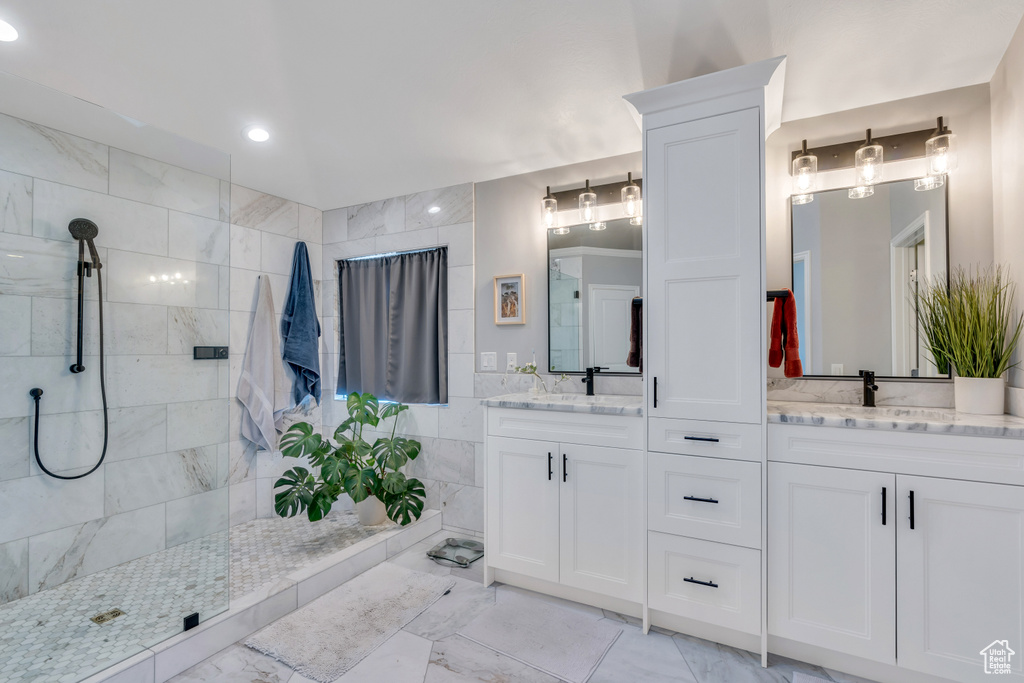 Bathroom featuring tiled shower, tile flooring, and dual vanity