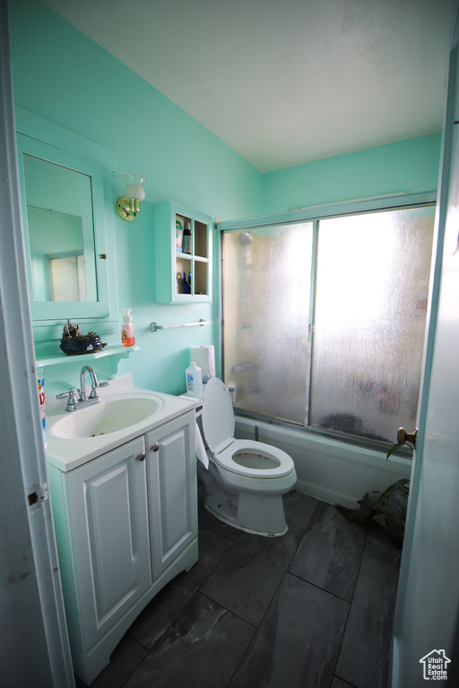 Full bathroom featuring vanity, shower / bath combination with glass door, toilet, and tile floors
